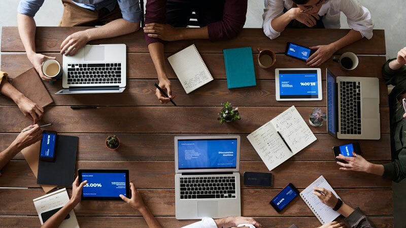 Top View Photo Of People Near Wooden Table with their laptops, pens and notepads Miami