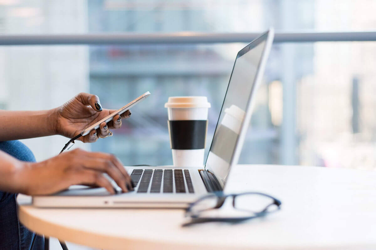 Image of someone checking through a laptop while holding a phone