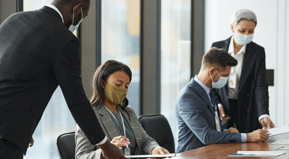 People working in an office setting, with nose masks on