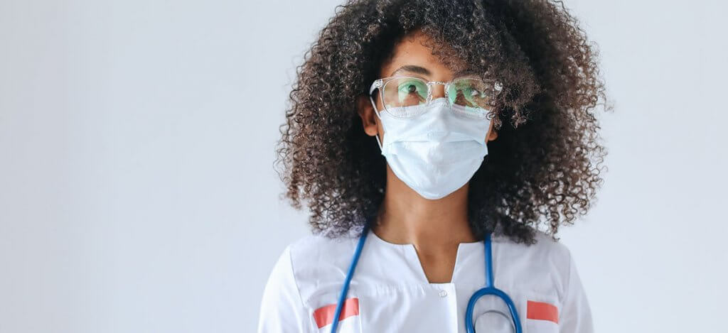 A woman wearing a white overall with a stethoscope around her neck