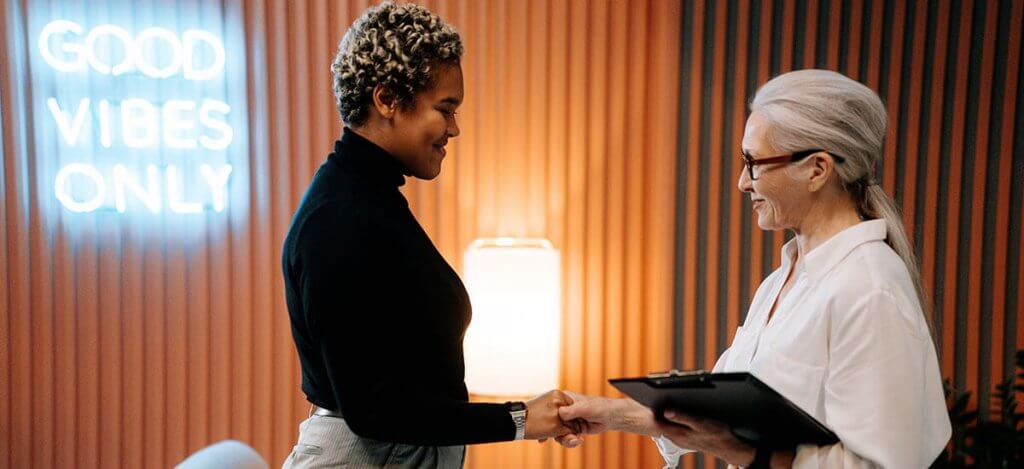 Two women shaking hands in an office setting