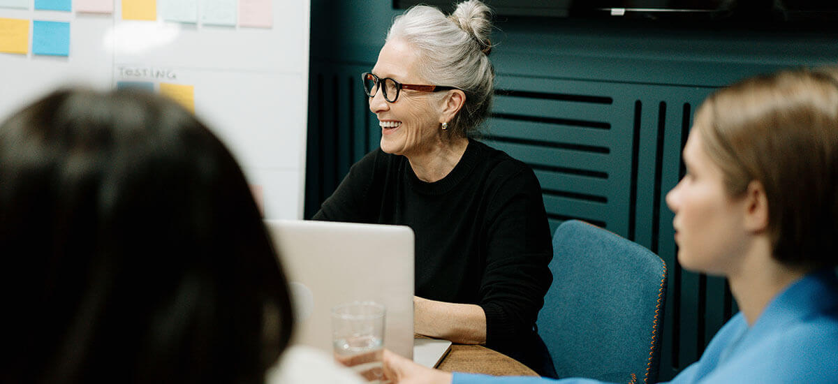 Woman in Black Sweater and Eyeglasses Sitting on Chair Beside Woman in Blue Shirt