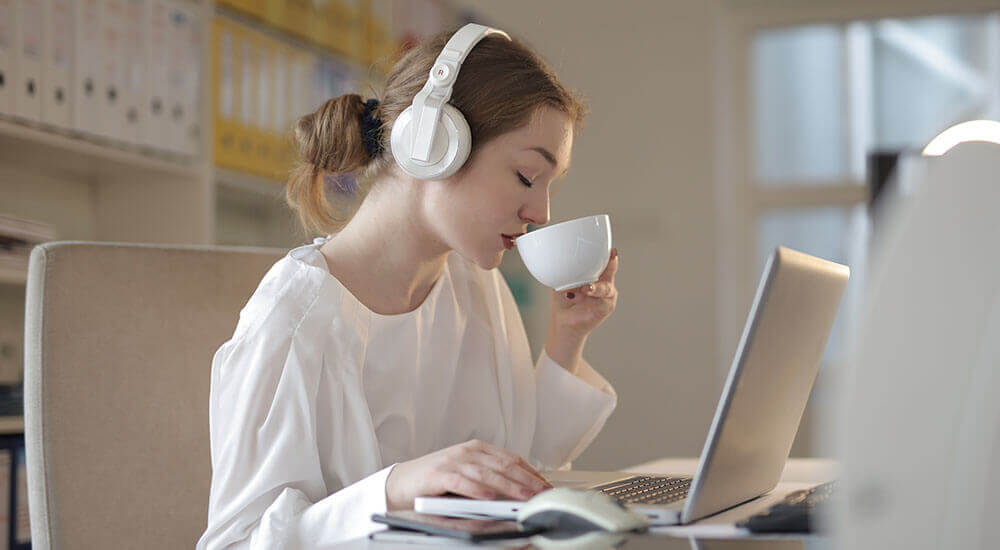 A remote worker drinking from a cup in front of a laptop - Riverside County