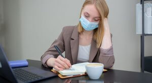A woman wearing face mask writing on a paper - Dallas County