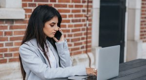 Woman calling using a phone in front of a laptop