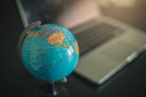 A globe replica on top of table with laptop blur in the background