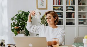 A woman showing a stack of cash to the person she's talking to online