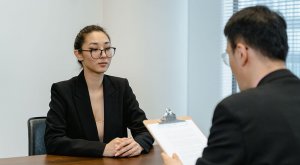 A woman in suit sitting across a man during an interview