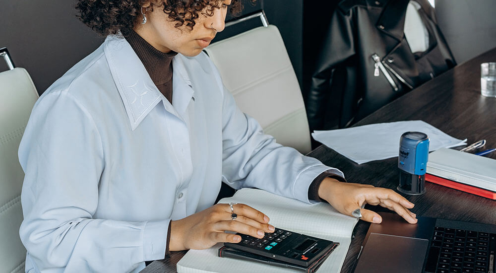 A woman pressing a calculator - Colorado - Careers In Government