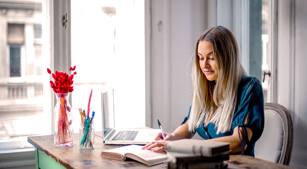 A woman writing on a desk in an office - Colorado - Careers In Government