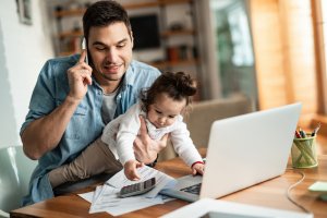 A working father holding his child while talking on phone