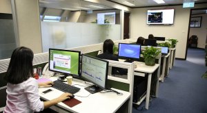 People in an office facing their desktop and working