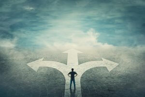 A person stands at a crossroads, facing three arrows pointing in different directions against a misty, cloudy sky. The figure appears contemplative, symbolizing a decision-making moment. The cobblestone path underfoot enhances the sense of uncertainty and choice, reminiscent of the labors ahead.