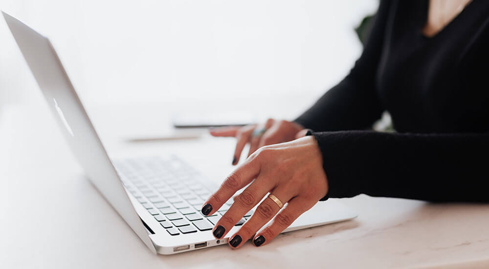 A hand about to press a laptop keybpard - Greenville - Careers In Government