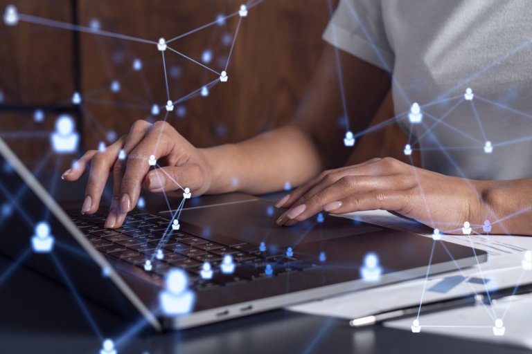 Hands typing on a laptop keyboard with overlay graphics of interconnected digital icons, suggesting a network or communication concept. The background is slightly blurred, focusing attention on the hands and the network graphics, emphasizing the essence of digital work connectivity.