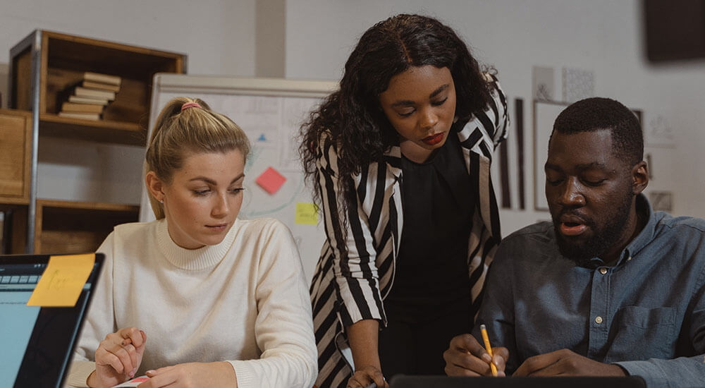 A man writing on a paper with two women beside him - Atlanta Georgia - Careers In Government