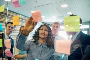 Business people using stickers and posting it on clear board