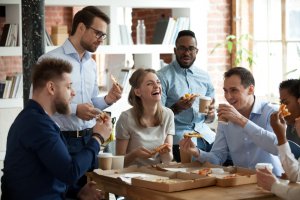 A happy diverse team talking and laughing on a joke while eating