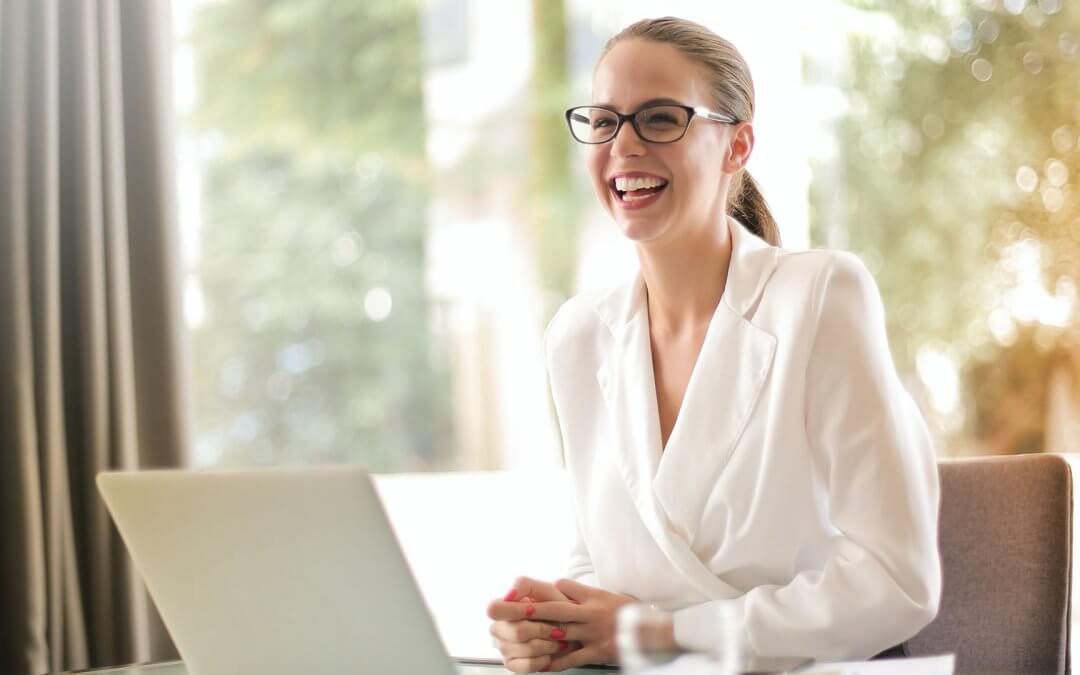 A lady in white blazers happily smiling in an office setting