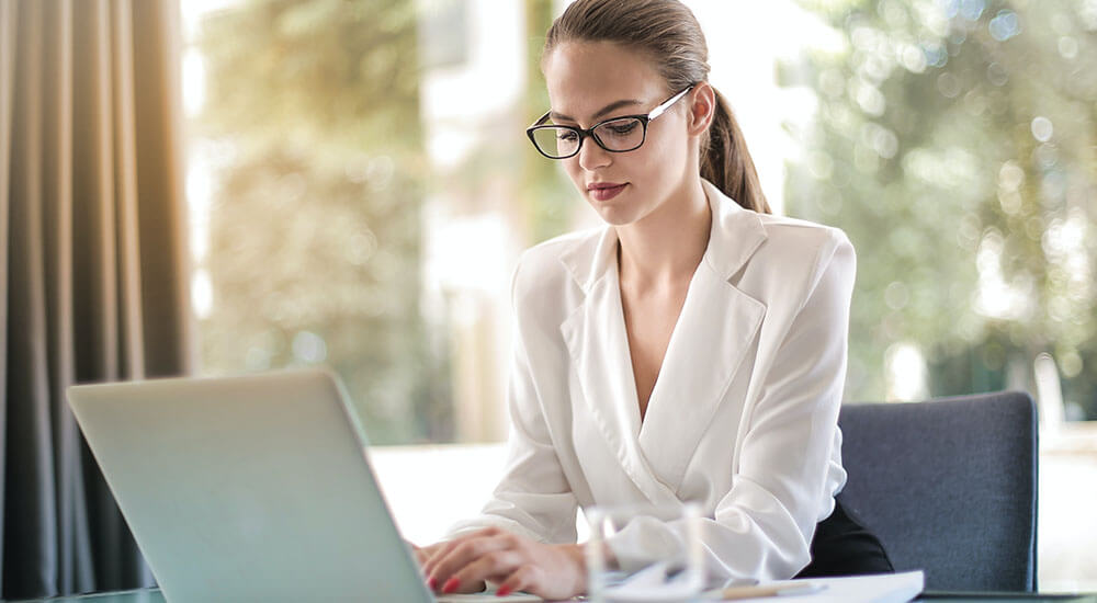 A woman wearing white blazer in front of a laptop - Charleston County - Careers In Government