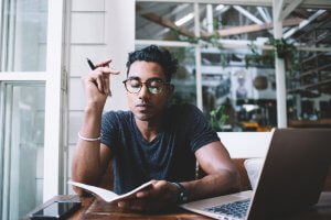 A Hispanic man in eyeglasses concentrating on writing