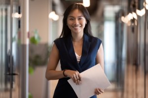A smiling Asian Businesswoman holding a pen and paper