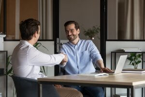 An employer and employee in an office setting shaking hands together