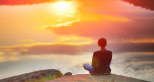 A woman sitting on top of the hill with the sea of clouds view