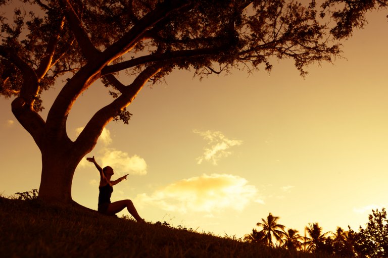 A woman sitting with hands raised on air enjoying the view of nature