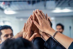 Joyful business people raise hands together