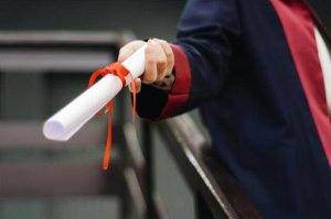 A graduate holding a temporary diploma given during graduation