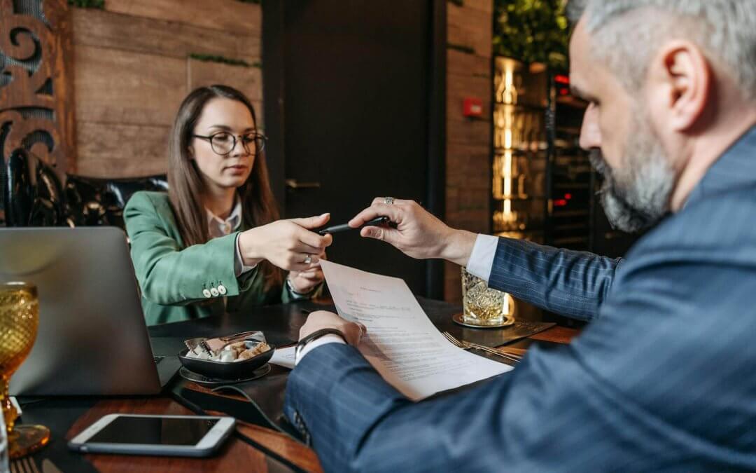 Employer taking a pen from a woman before signing a paper