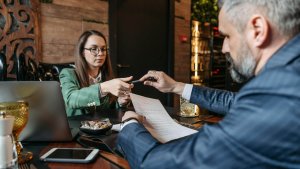 Employer taking a pen from a woman before signing a paper