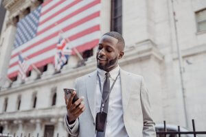 An African American man, in front of a building with a flag.