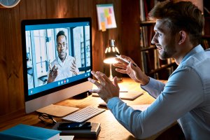 Caucasian businessman talking with an African male partner virtually