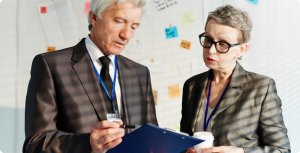 An old man and woman employee checking file together