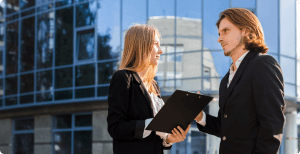A man and a woman in formal suits discussing ideas outside their workplace