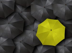 Many blacks and one distinct yellow umbrella as a concept for leadership
