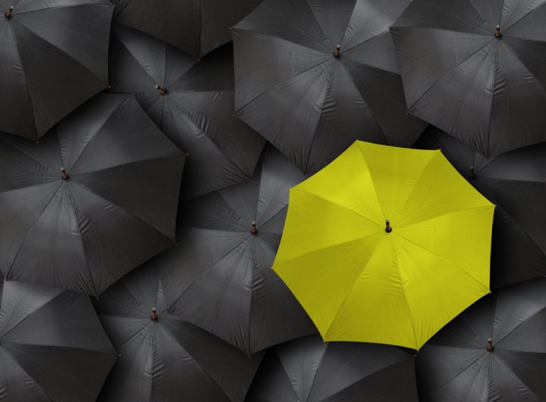 Many blacks and one distinct yellow umbrella as a concept for leadership