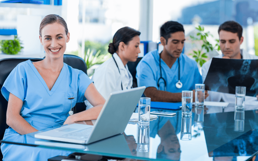 Happy doctor smiling at the camera while her colleagues analyzes an xray