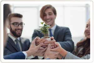 A group of employees holding a small pot with plants