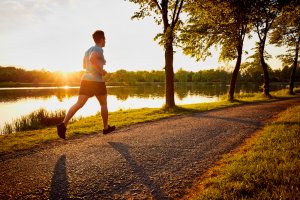 A young man jogging in a nature park at dusk