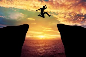 A man jumped through the gap between hills situated in an ocean