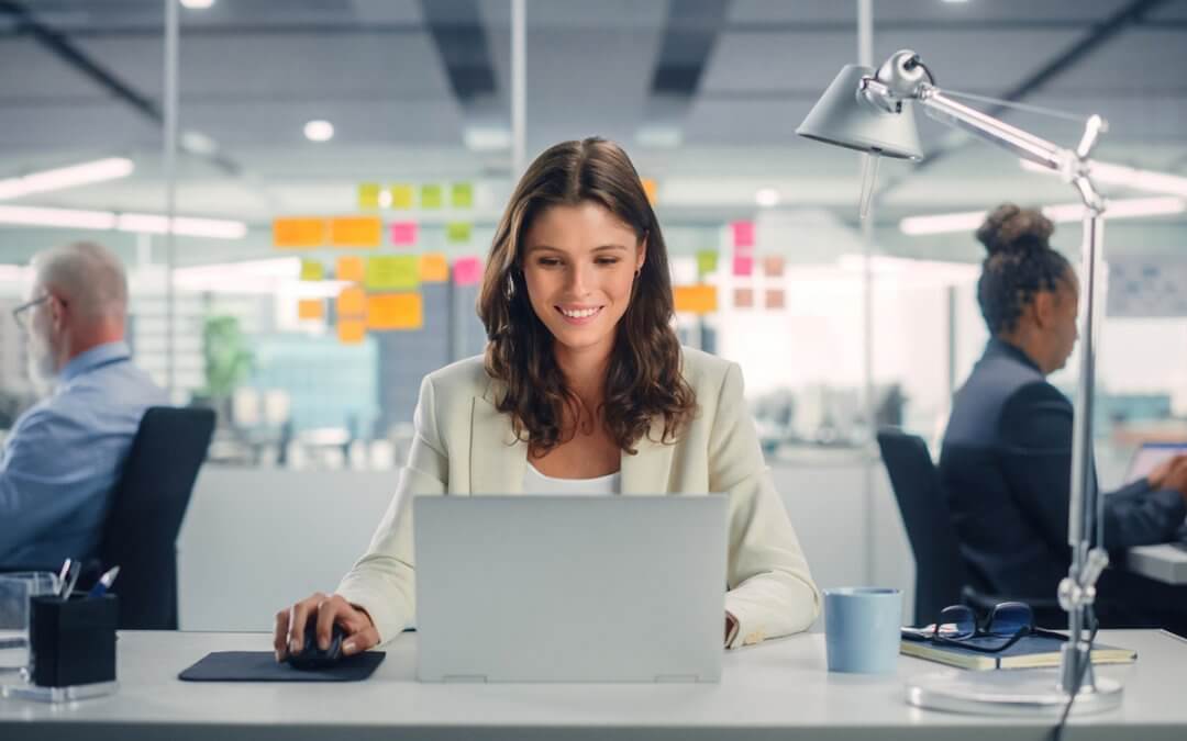 A woman happily working in the office with her colleagues