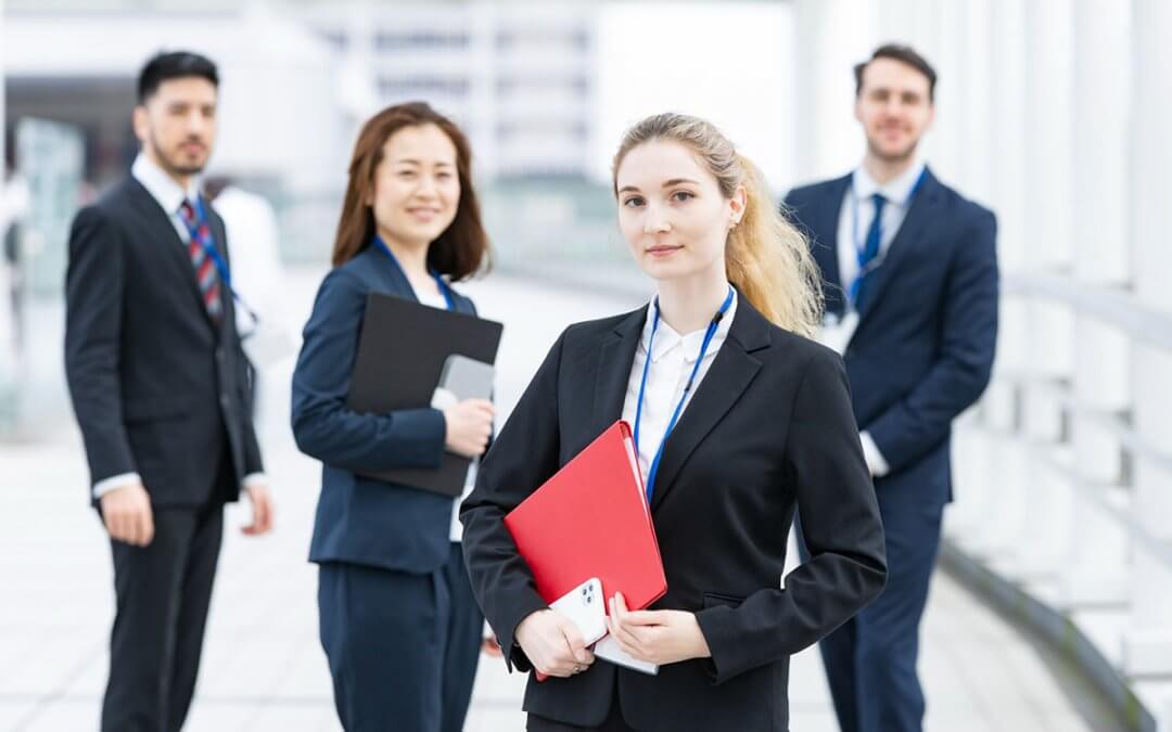 Four employees standing proudly outside the company building