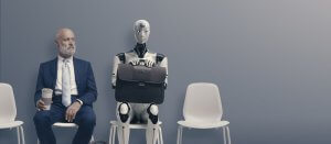 A bald man in a blue suit holding a coffee cup sits on a white chair next to an AI humanoid robot holding a briefcase. Both are seated against a clean, grey wall, each occupying white chairs with one empty chair between them. The scene has a minimalist aesthetic.