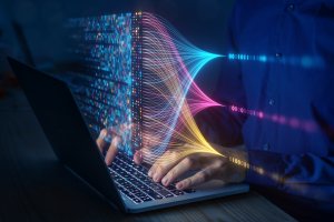 A person working on a laptop with colorful data visualizations, powered by AI, emanating from the screen, symbolizing data processing and digital information analysis. The visualizations include bright lines and binary code, creating a dynamic and futuristic scene.