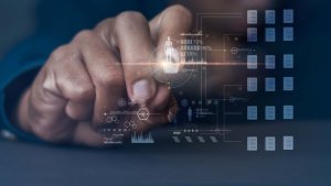 A hand interacts with a digital interface displaying various tech icons, graphs, and data visualizations. The holographic elements suggest AI-driven information processing and analytics, creating a high-tech, futuristic atmosphere.