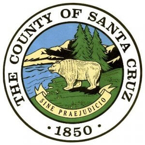 Official seal of Santa Cruz County, featuring a bear standing near a lake with trees and mountains in the background, encircled by the text "The County of Santa Cruz 1850" and the Latin motto "Sine Praejudicio.