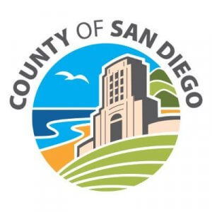 The logo for the County of San Diego features a stylized building near the coast with green hills, a beach, the ocean, and two birds in the sky, encircled by the words "County of San Diego.